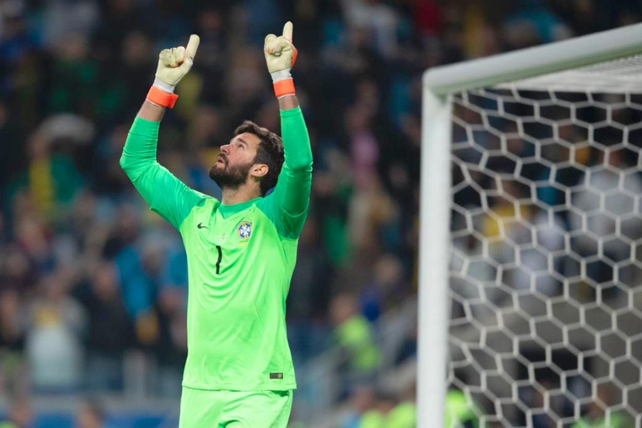 A goalkeeper looks up and points his two index fingers towards the sky.