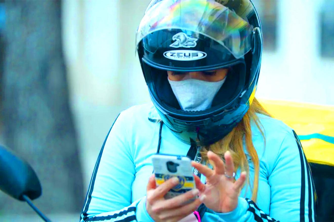 A woman wearing a helmet looks at her phone. 